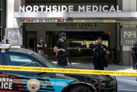 A photo of police officers standing behind crime scene tape at the Northside Medical Midtown medical office.