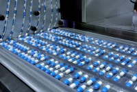 A photo of packages of pills on a conveyor belt in a factory.