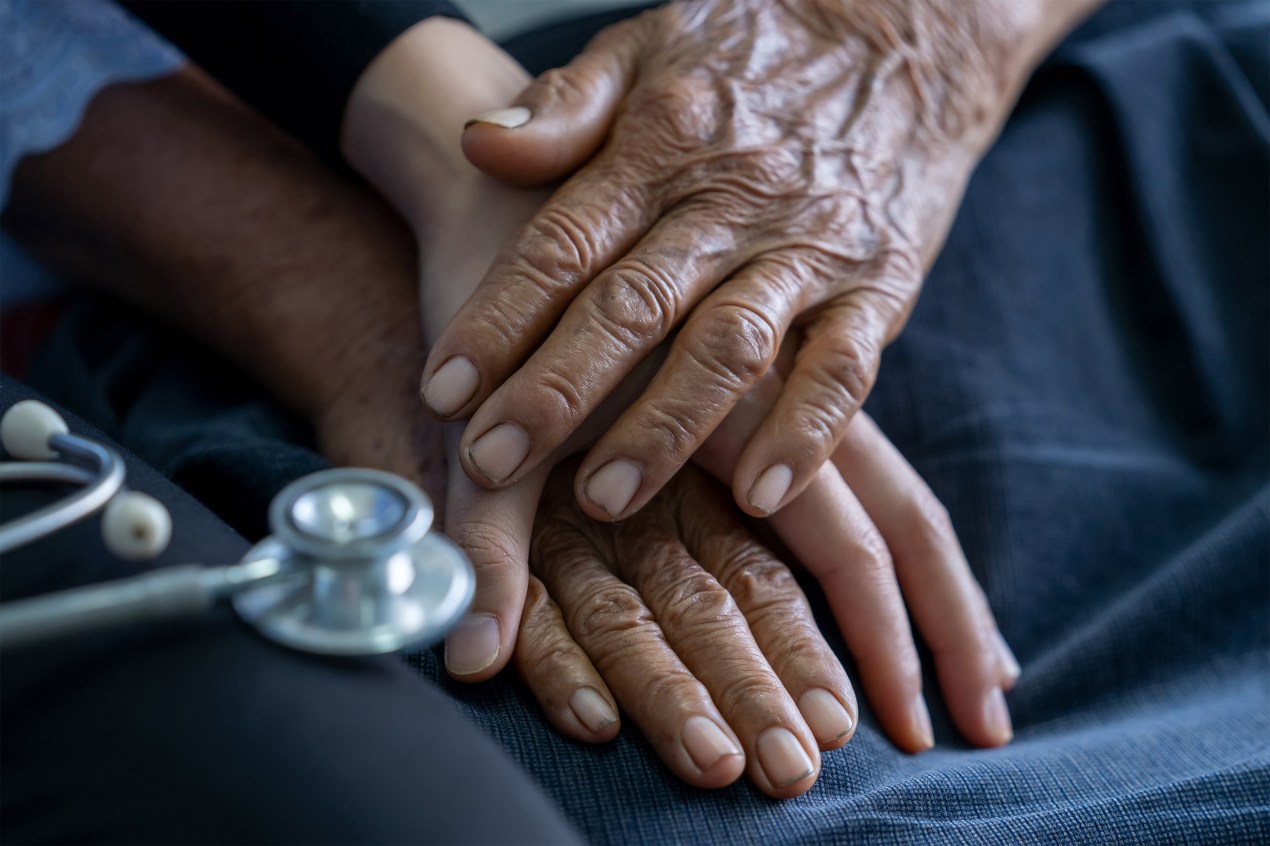 A photo of a medical caregiver holding an elderly patient's hands.
