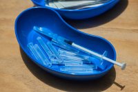 A photo of a covid-19 vaccine on a blue dish.