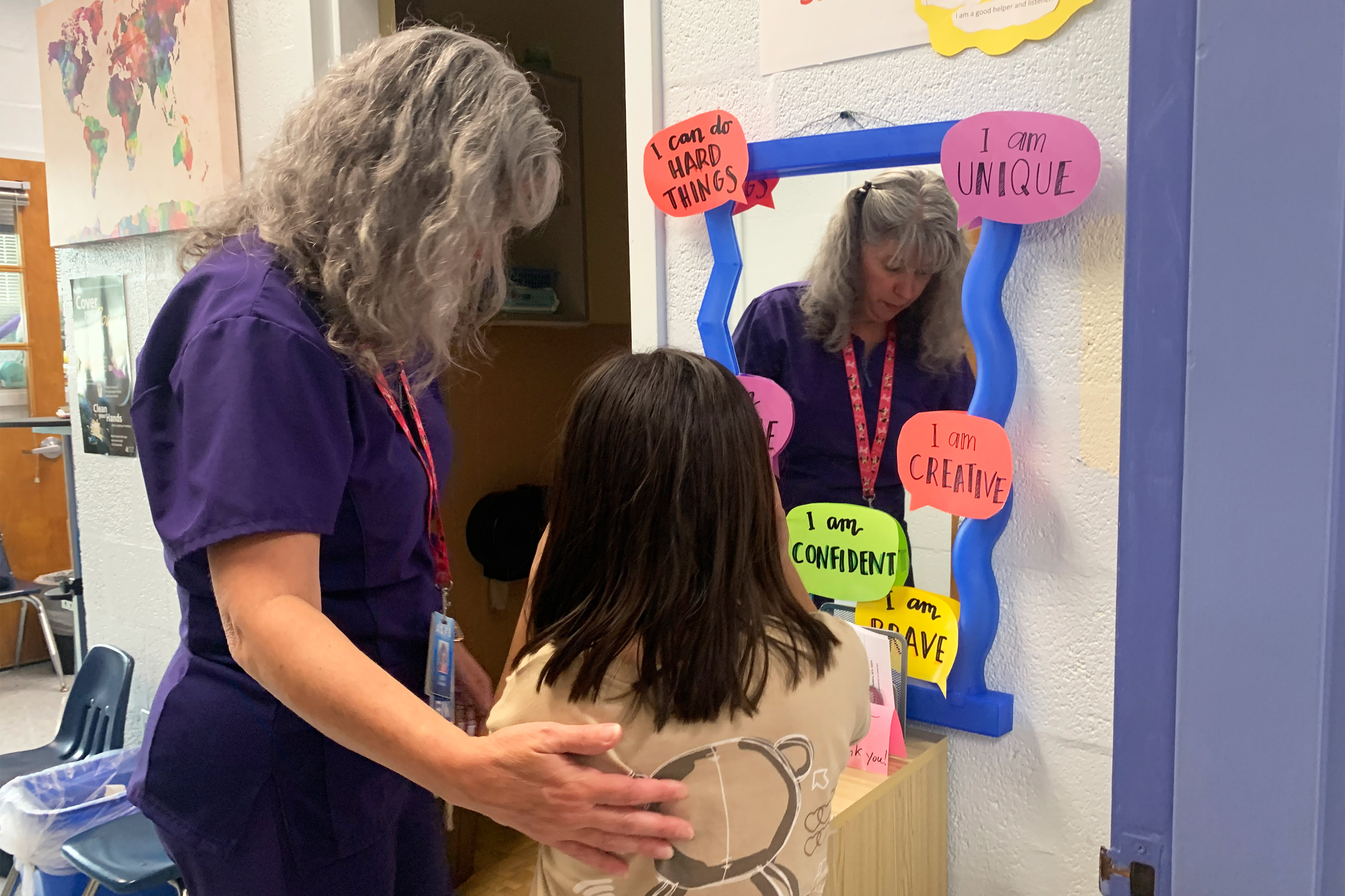 A photo of a nurse speaking to a child inside of a nurse's office.