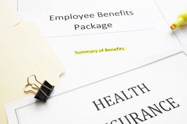 Papers that read "Emplouee Benefits Package", "Summary of Benefits", and "Health Insurance". There is a yellow highlighter and a binder clip on top of the papers.