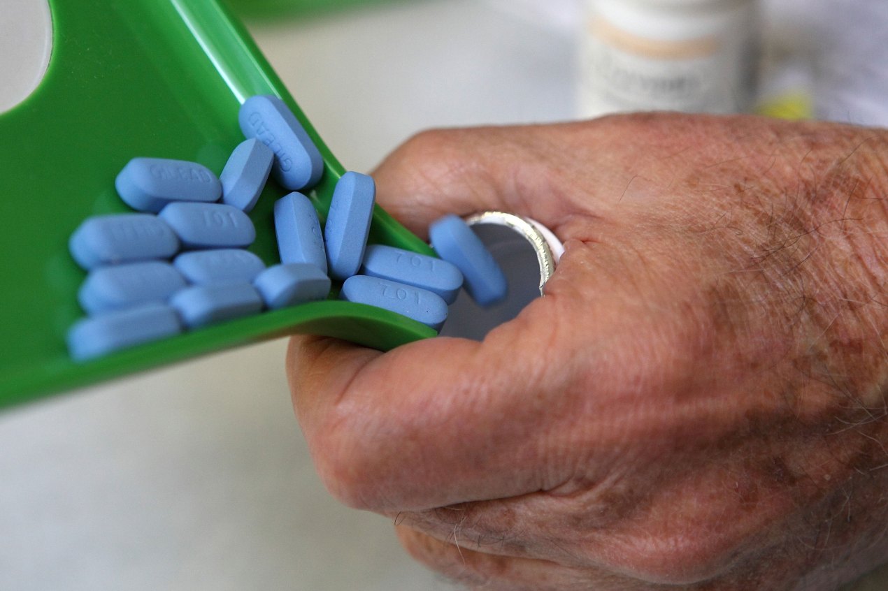 A photo of a pharmacist pouring blue Truvada pills into a bottle.
