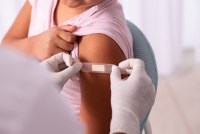 A medical healthcare worker puts a bandage on a child's arm after vaccination.