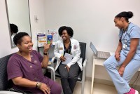 YaSheka Shaw, a patient, sits to the left of medical student Kaniya Pierre Louis (center) and physician Zita Magloire (right).