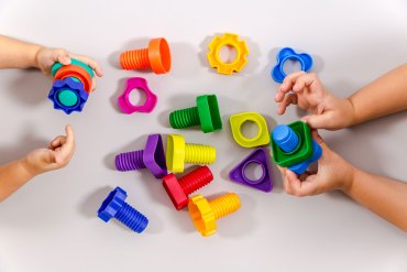 Hands of two children playing with colorful constructor toys.